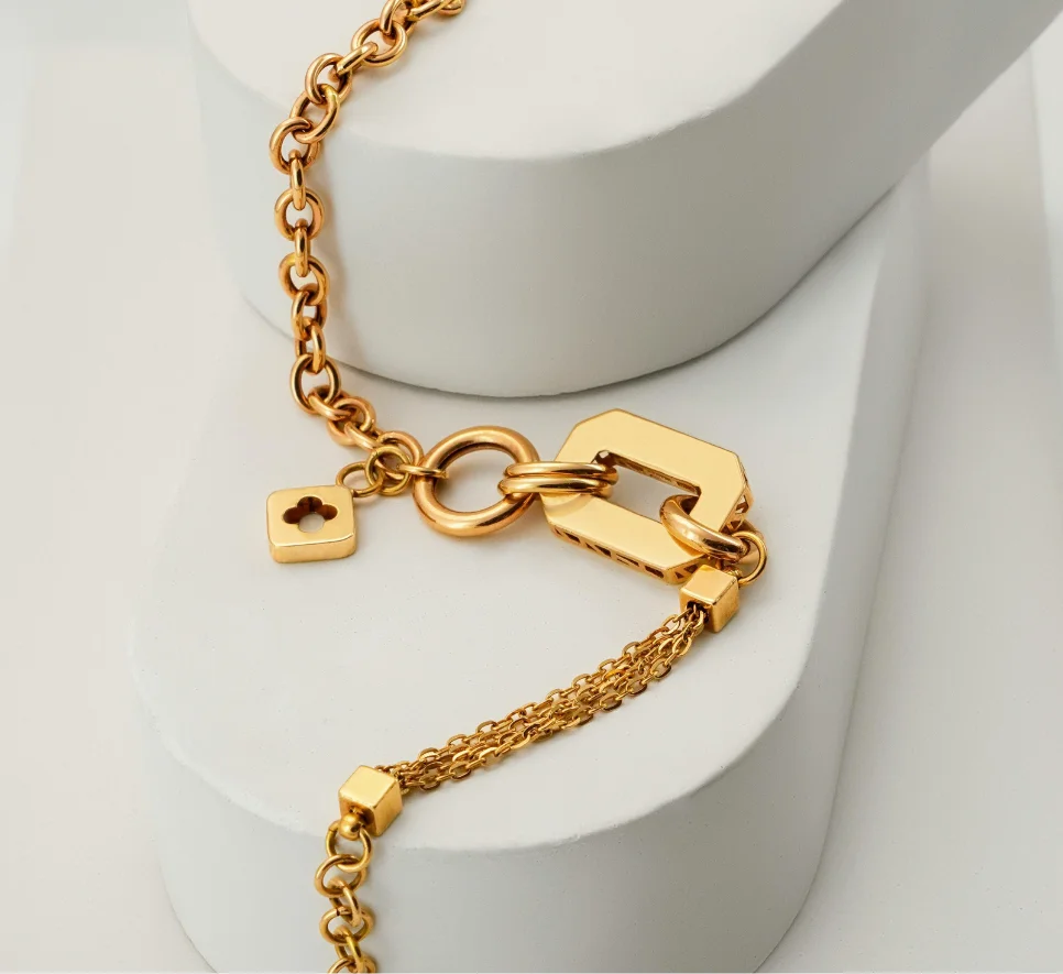 Joyería Pulsera de oro con cadena gruesa, broche decorativo y colgantes sobre fondo minimalista